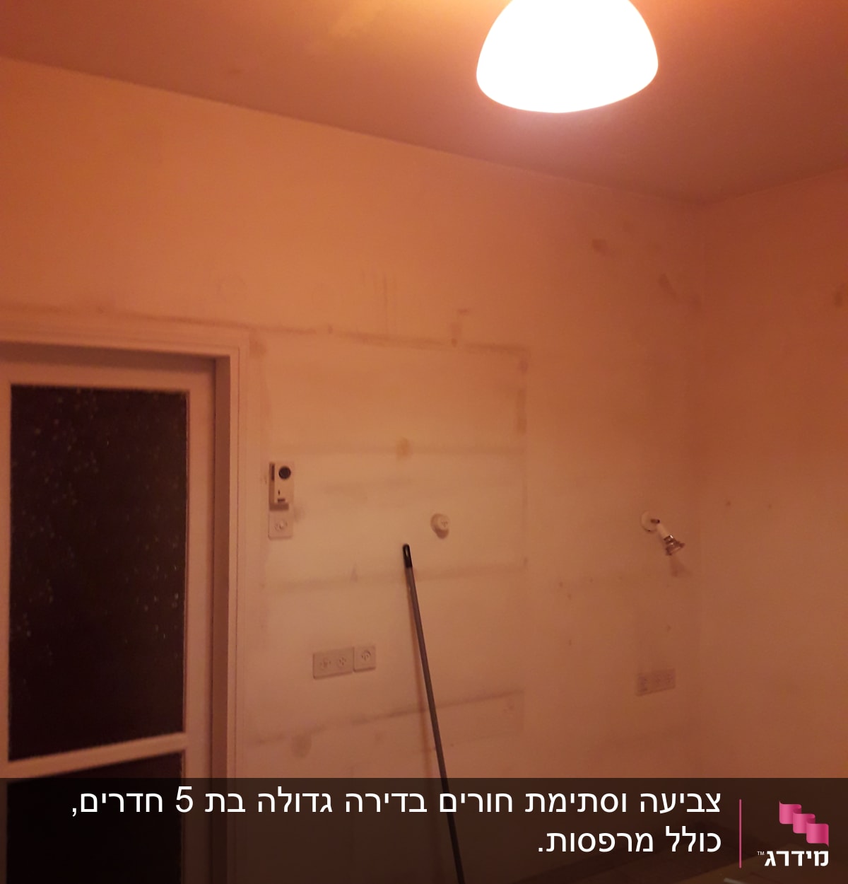 קיר צבוע עם סימני צבע, מטאטא נשען על הקיר